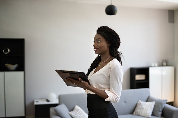 Woman holding tablet in modern living room with gray sofa and black pendant light